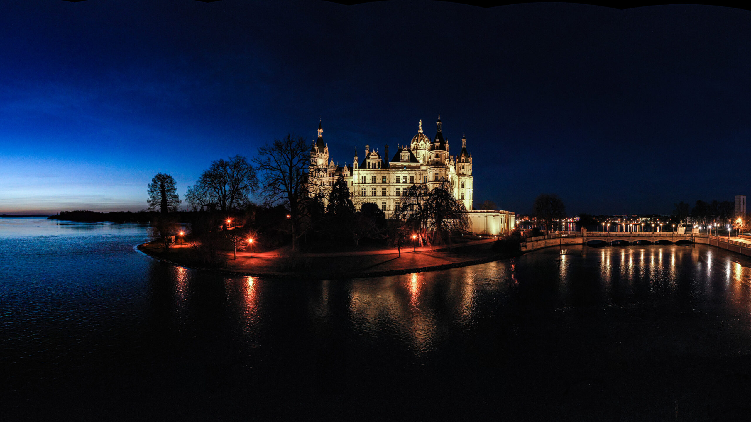 Stitched Panorama a large building with a body of water at night