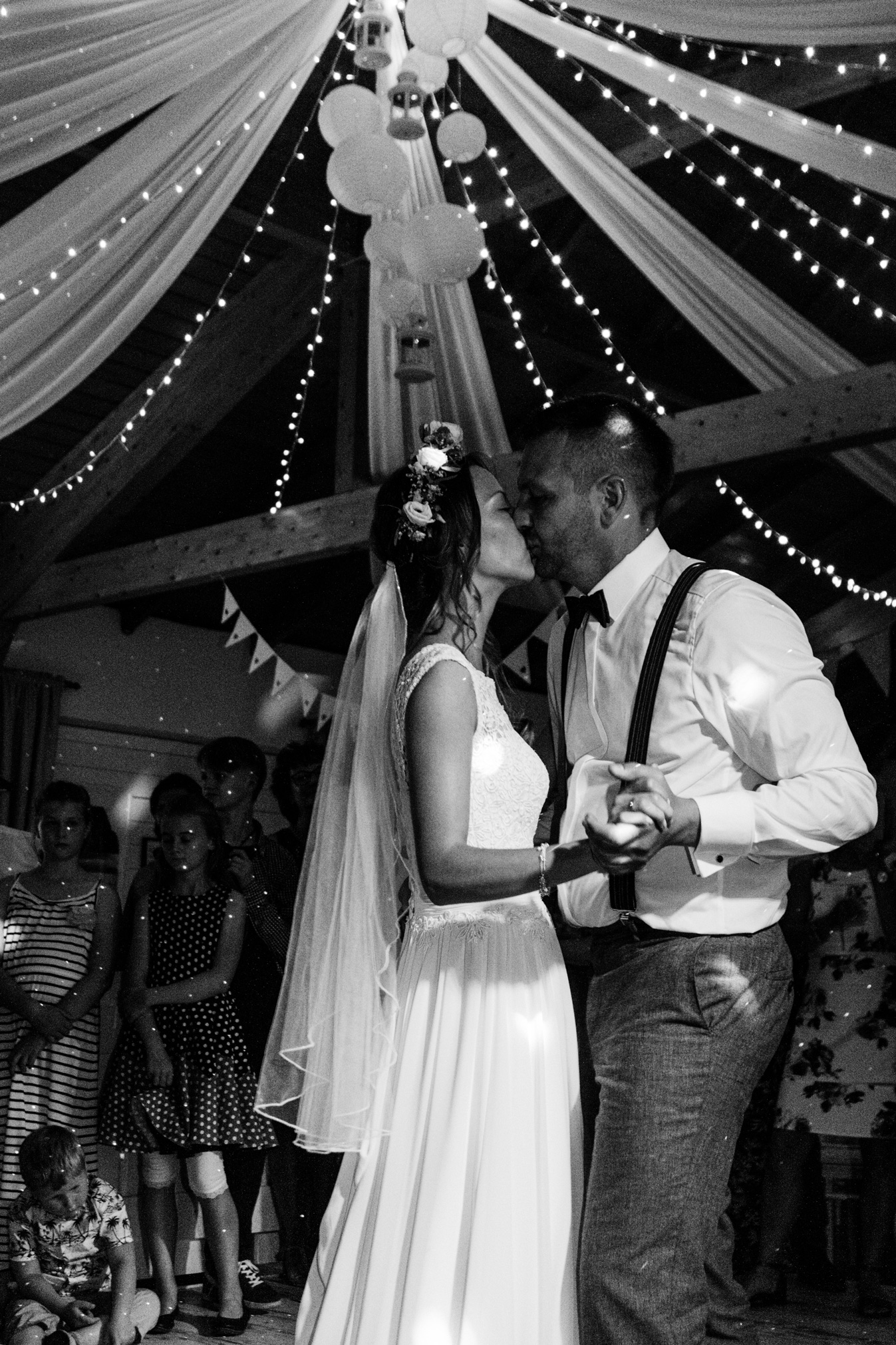 5B6A3925 a man and woman kissing in a room with people watching weddingdance
