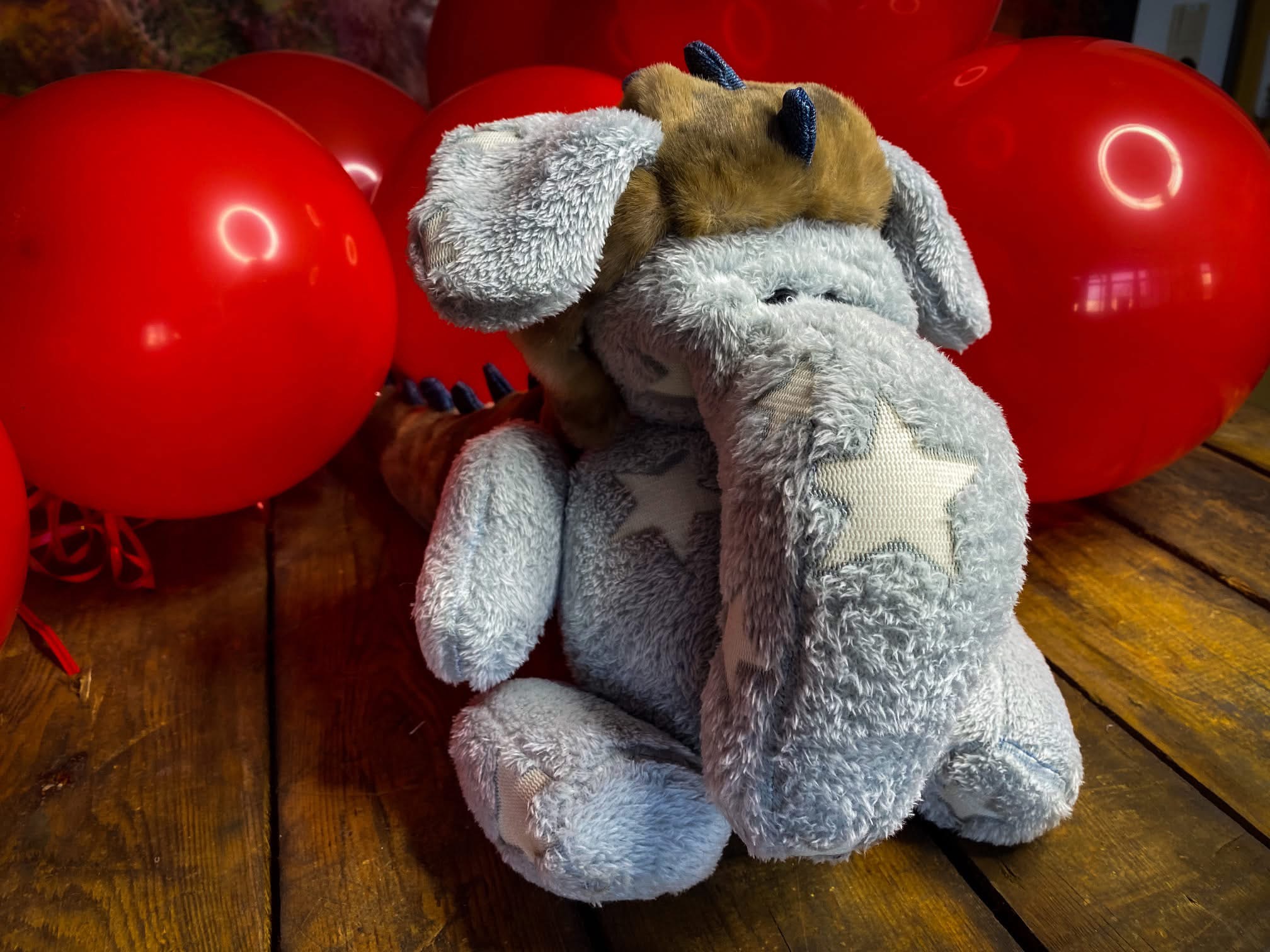 Elefantendrache-Isabella-brian-lorenzo-1 Handgemachtes Kuscheltier Elefantendrache Isabella aus flauschigem Stoff mit Sternenmuster, umgeben von roten Luftballons. Perfekt für Kinder und als besonderes Geschenk.