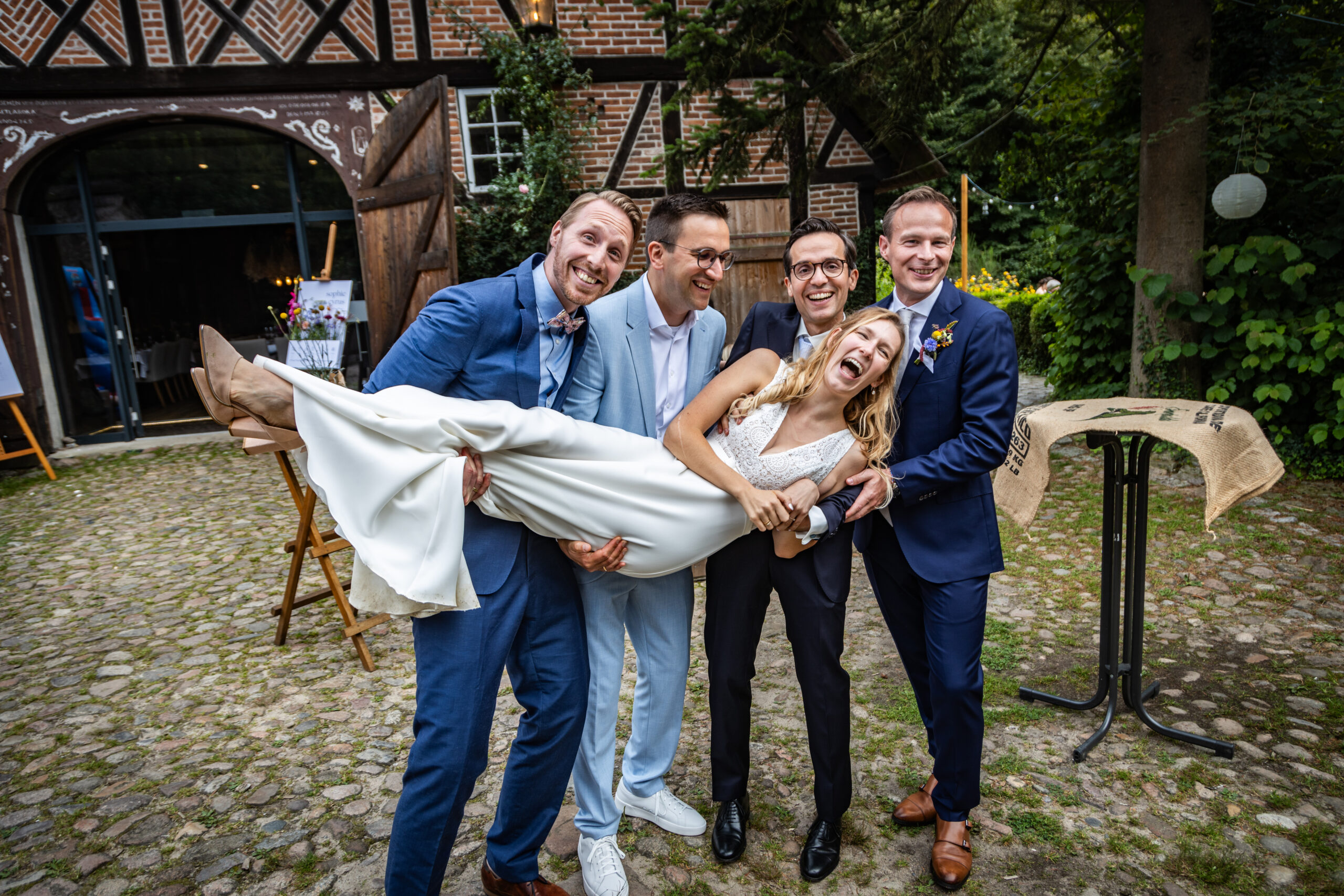_MG_7511 Braut wird lachend von vier Männern auf dem Hof des Forsthaus Waldmühlen in Lübeck getragen