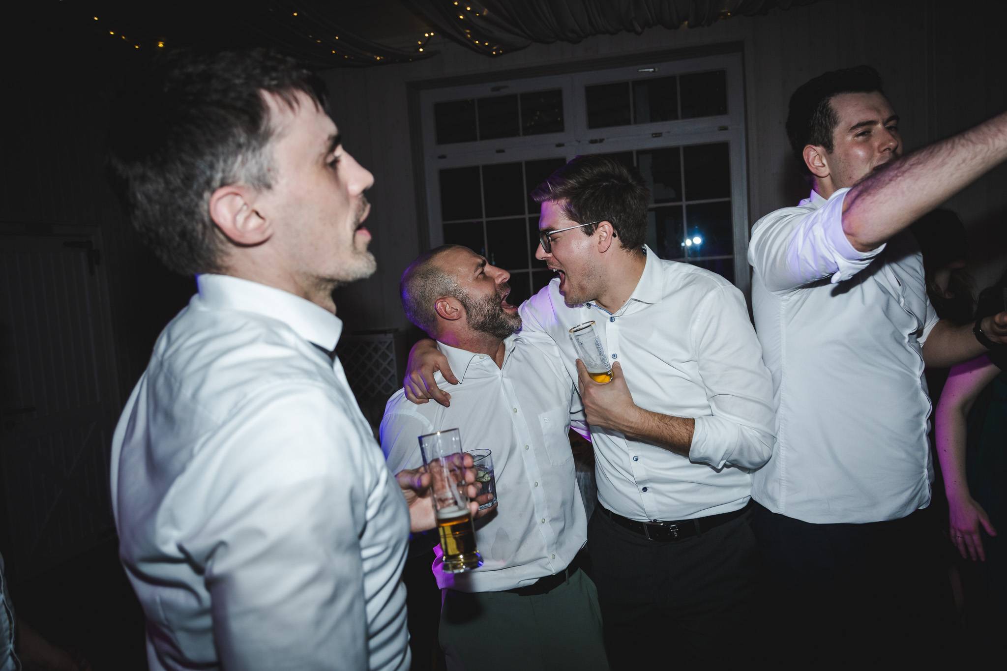 Hochzeitsfeier-Direct-Flash-Party-Stimmung Dynamisches Hochzeitsfoto mit direktem Blitzlicht, das die ausgelassene Stimmung und Energie der Tanzfläche und feiernder Hochzeitsgäste einfängt.