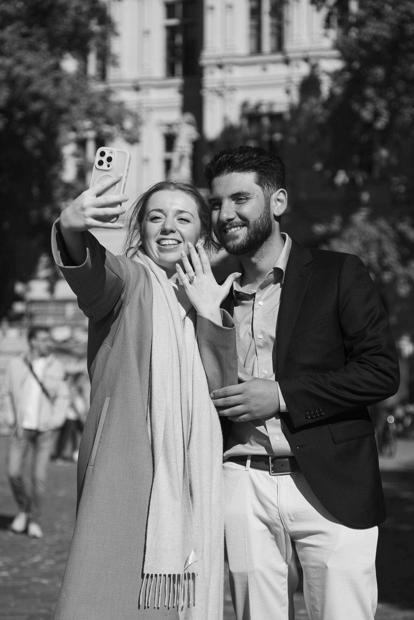 paar-macht-verlobungs-selfie-in-schwerin Ein frisch verlobtes Paar macht ein fröhliches Selfie in Schwerin; die Frau hält das Smartphone und zeigt dabei stolz ihren Verlobungsring in die Kamera.