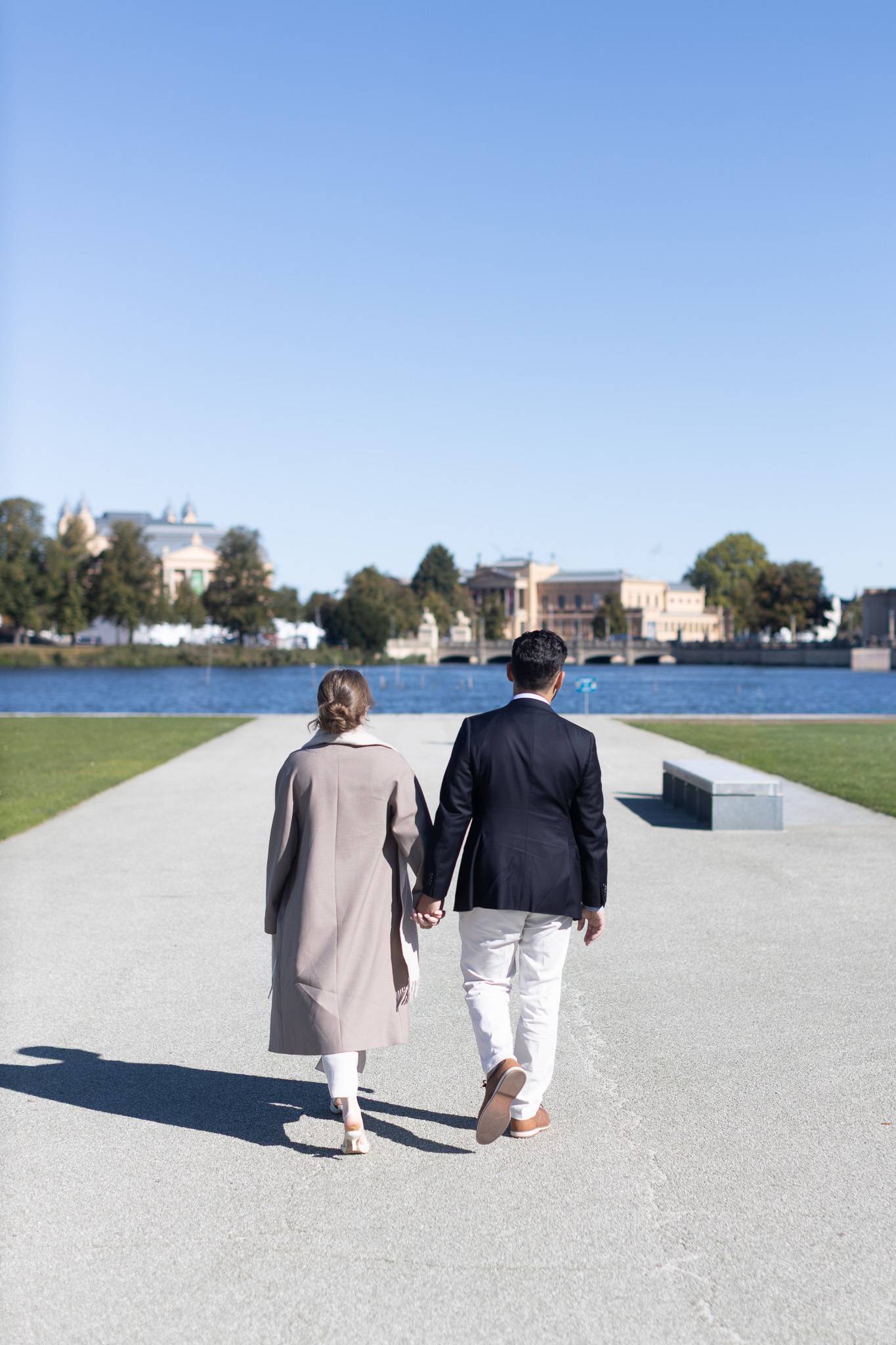 verlobtes-paar-geht-gemeinsamen-weg-schwerin Ein frisch verlobtes Paar geht Hand in Hand von der Kamera weg auf einem Weg am Seeufer in Schwerin, als Symbol für ihren gemeinsamen Weg in die Zukunft.