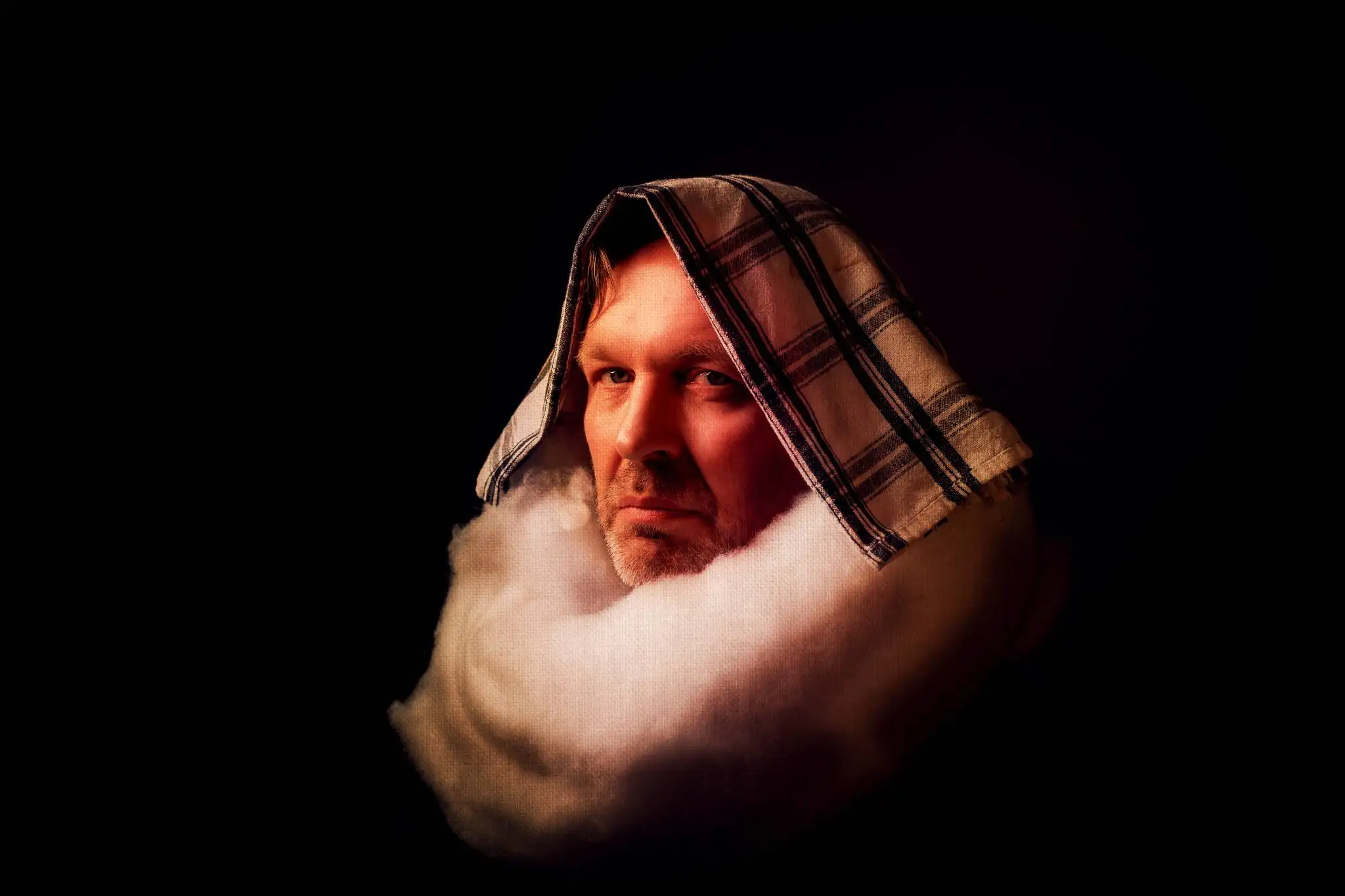 Künstlerisches Rembrandt Porträt fotografiert mit dramatischem Seitenlicht und Low-Key Beleuchtung. Portrait mit türkischem Turban und Leinentuch, charakteristische Lichtmodellierung, warme Farbtöne. Klassische Alte-Meister Kunstfotografie – Brian Lorenzo Tutorial Beispiel